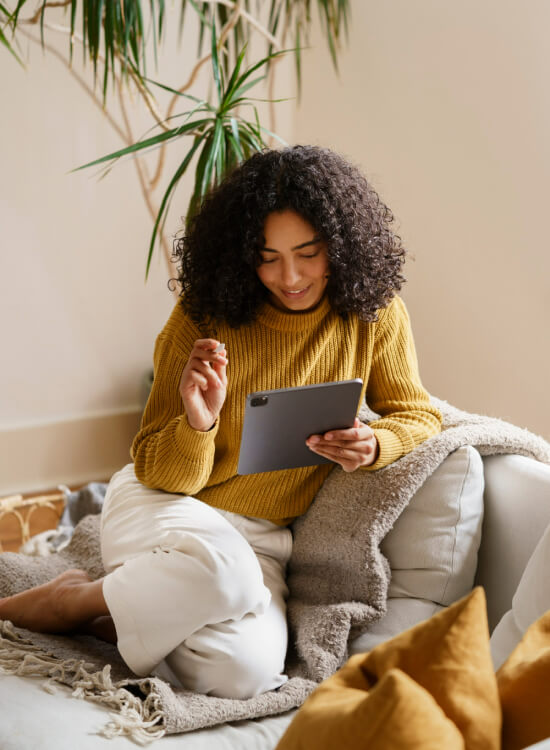 Woman Sitting on a Couch Looking At A Tablet