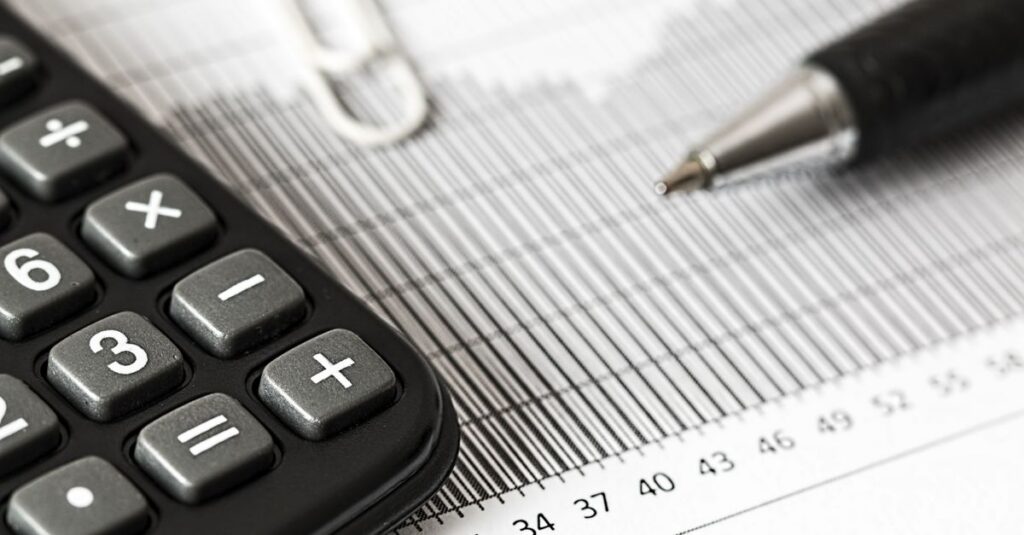 Close-up of a calculator and pen on a bar graph, representing finance and accounting.
