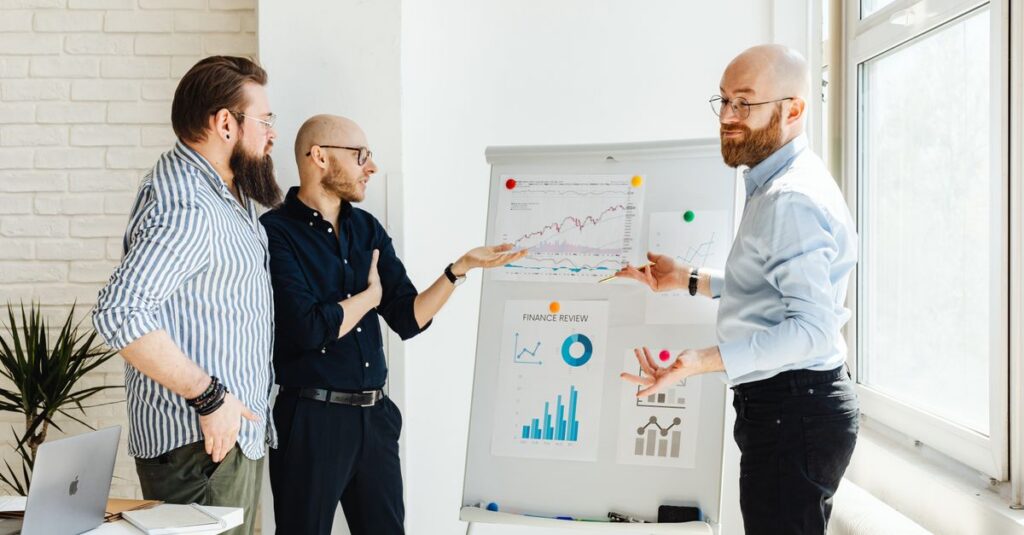Three colleagues discussing financial charts during a business meeting in a modern office setting.