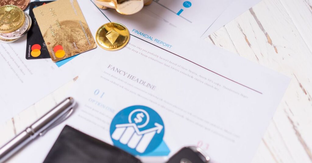 Close-up of financial documents, credit cards, coins, and a pen on a wooden desk.