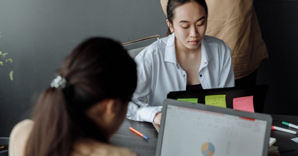 Young professionals collaborating in a modern office with laptops and documents.