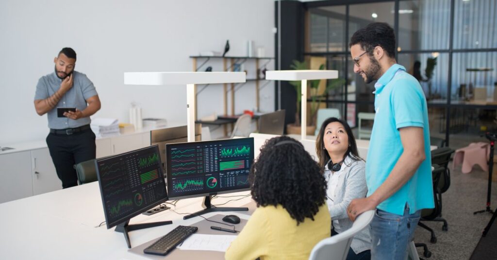 Office employees collaborate on financial data at modern workspace, engaging in teamwork and communication.