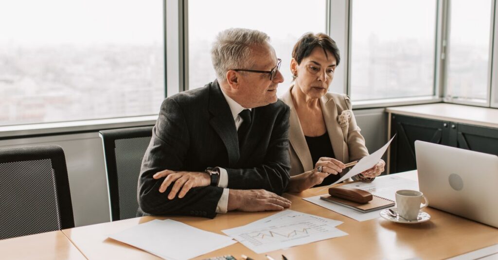 Two business professionals analyzing financial papers in a modern office setting.