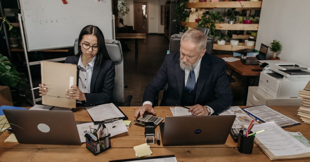 Business professionals in a modern office working collaboratively at desks with laptops.
