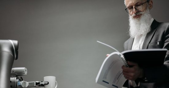 Elderly man reads as a robotic arm holds a coffee cup, showcasing technology integration.