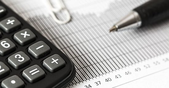 Close-up of a calculator and pen on a bar graph, representing finance and accounting.