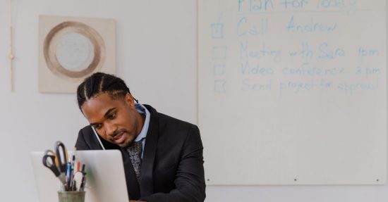 Businessman at his desk in an office working on a laptop and making phone calls.
