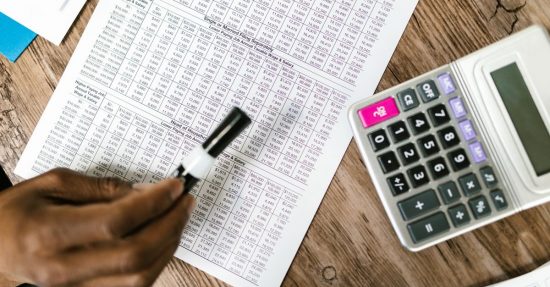 Close-up of tax documents and calculator on wooden table, highlighting financial analysis.