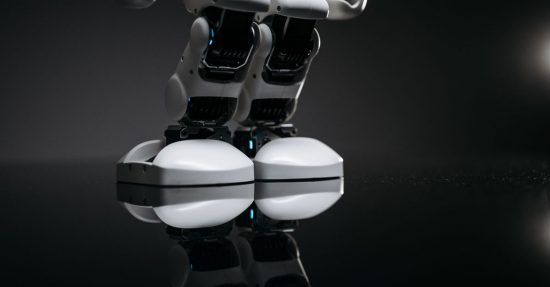Close-up of robotic legs reflecting on a glossy surface in a studio setting.