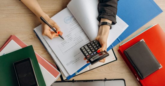 Accountant analyzing financial documents with a calculator on a desk, highlighting business tasks.