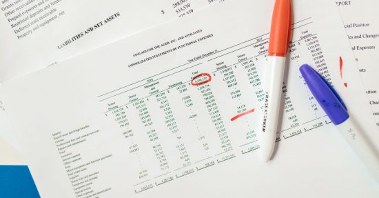 Close-up of financial documents with highlighted figures and marker pens.