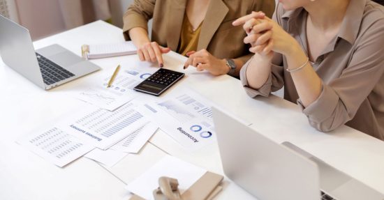 Two professionals collaborating on financial documents in a modern office setting.