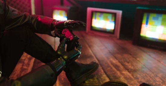 Futuristic cyberpunk vibe with a prosthetic hand holding a gaming joystick. Neon lights and retro TVs.